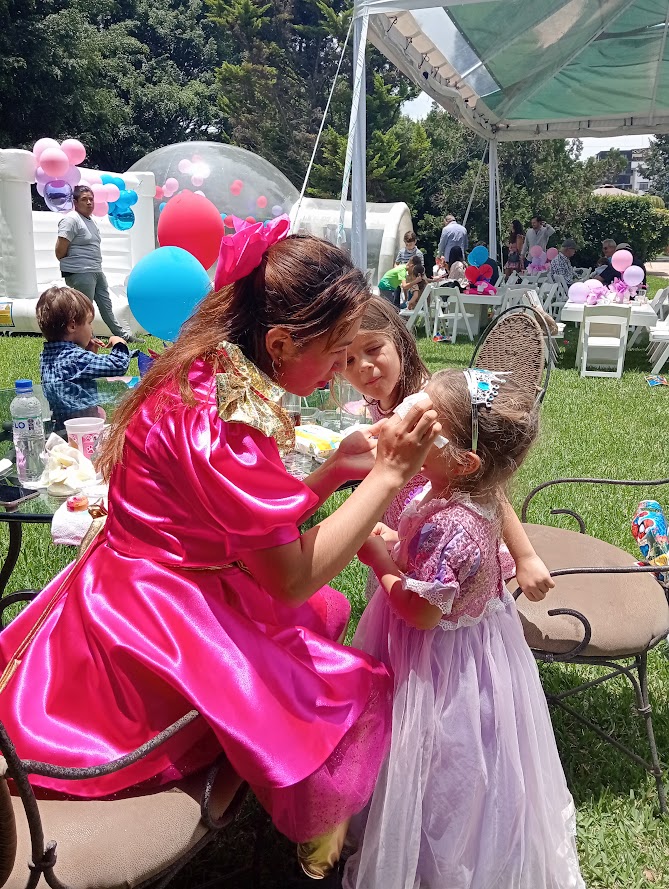 Animadora pintando el rostro de una niña durante una fiesta